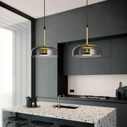 Two decorbites led glass pendant lights with gold rods and translucent led glass bowl shades above kitchen island