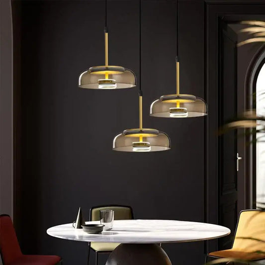 Three modern DecorBites LED glass bowl pendant lights with gold metal stems and smoked glass shades for dining use