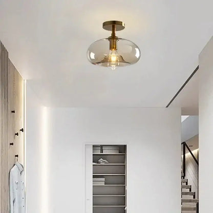 A decorbites led glass ceiling light with a brass-finished metal base and smoke-colored glass dome for modern interiors