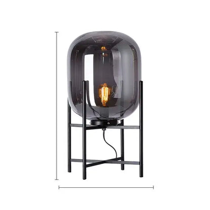 A sleek dark gray smoked glass decorbites led glass floor lamp with black metal frame and exposed filament bulb