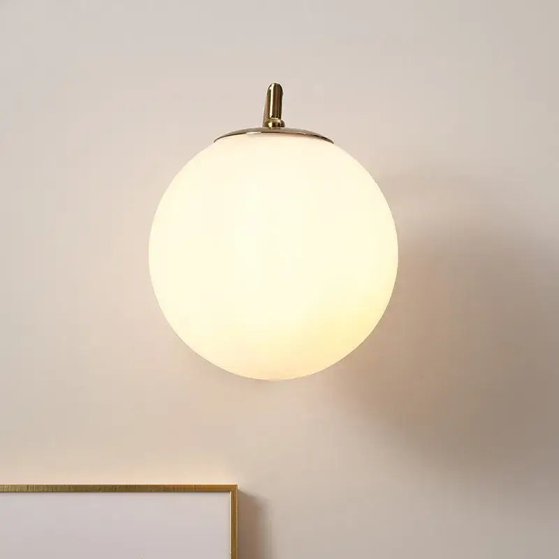 A warm glowing DecorBites LED glass iron wall light with frosted globe and brass finish for living room or corridor