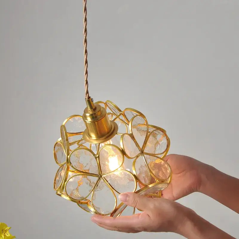 A delicate gold-toned decorbites led glass pendant light with clear flower-shaped panels for modern kitchen decor