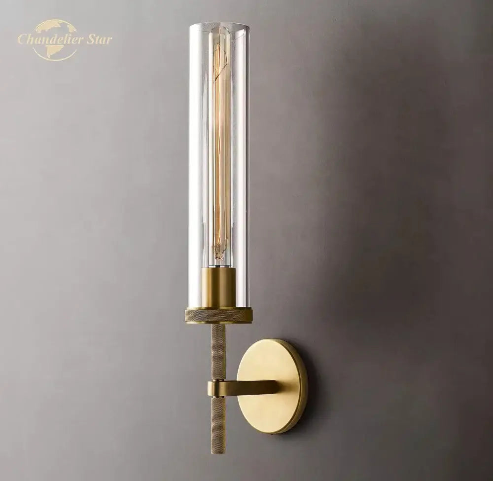 Gold-toned decorbites led glass wall sconce with clear glass cylinder and exposed filament bulb for indoor use