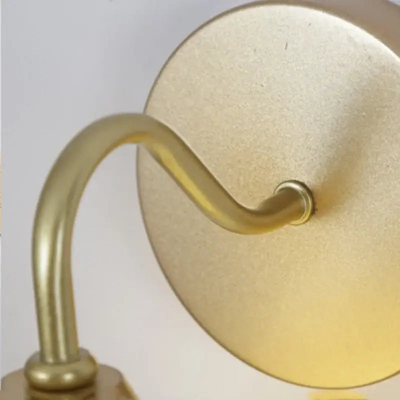 Gold-finished brass decorbites led glass wall sconce with curved arm and circular backplate for modern stair lighting