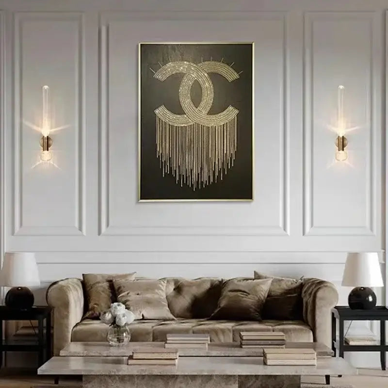 Gold chanel logo artwork with sparkling embellishments and dangling chains on decorbites™ gold glass wall sconces