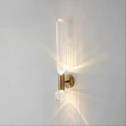 Decorbites™ gold glass wall sconces feature a clear ribbed glass tube and faceted glass globe on a brushed brass fixture