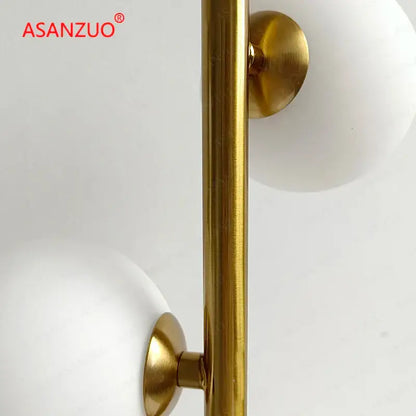 DecorBites table lamp with gold-finished metal pole and milk white glass lampshade featuring white glass spheres