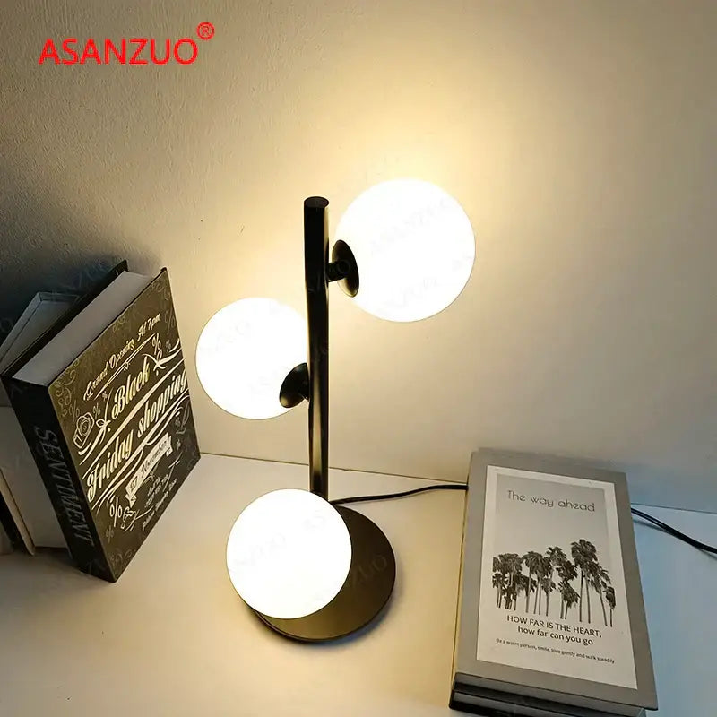 Modern black metal table lamp with three glowing milk white glass lampshade globes from DecorBites™ LED collection