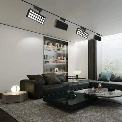 Black leather sectional sofa with tufted cushions and dark gray throw pillows under decorbites led grille track light