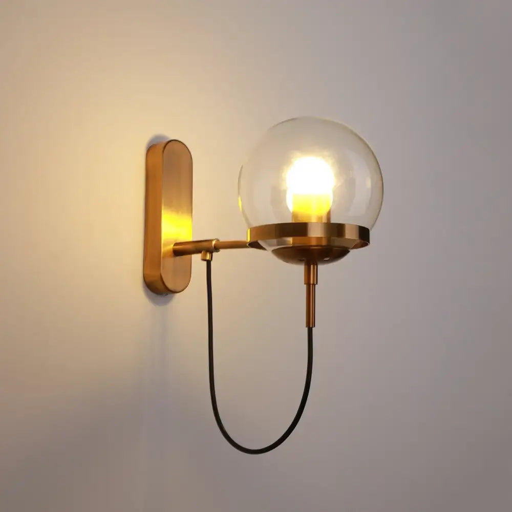 Brass-finished DecorBites™ LED indoor wall lamp with spherical glass globe housing illuminated bulb for home decor