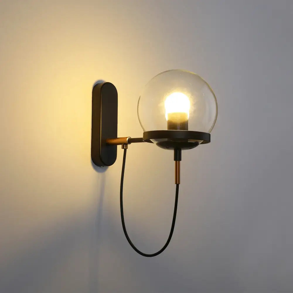 Modern black and brass decorbites led indoor wall lamp with a clear glass globe for living room and bedside lighting
