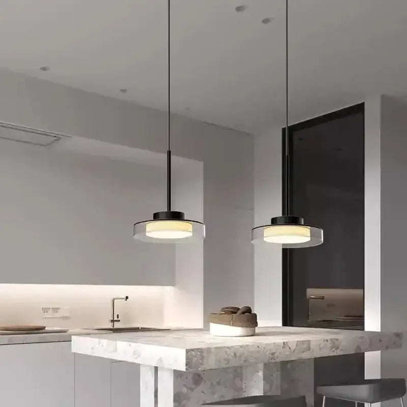 Two minimalist black decorbites led iron acrylic pendant lights with frosted shades above marble countertop