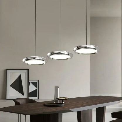 Three polished chrome decorbites led iron pendant lights with circular diffusers in a minimalist dining space