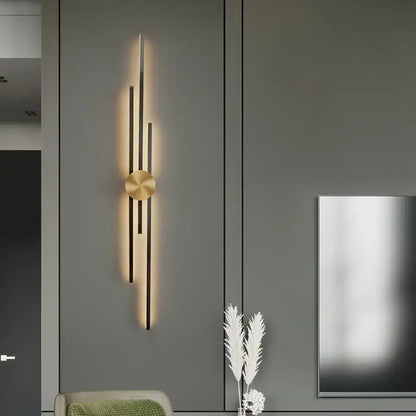 Modern gold-toned decorbites led long wall lamp with vertical rods and circular base emitting warm light on dark cabinetry