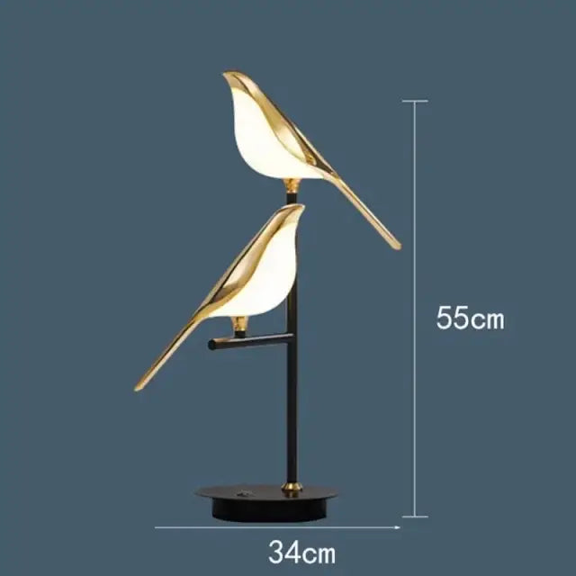 Gold-toned decorbites led magpie bird pendant light with illuminated translucent bodies on a sleek black stand for modern decor