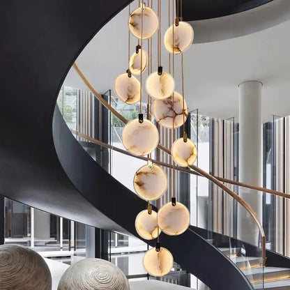 A modern decorbites led marble pendant lamp with warm-toned marble orbs and brass chains for living room lighting