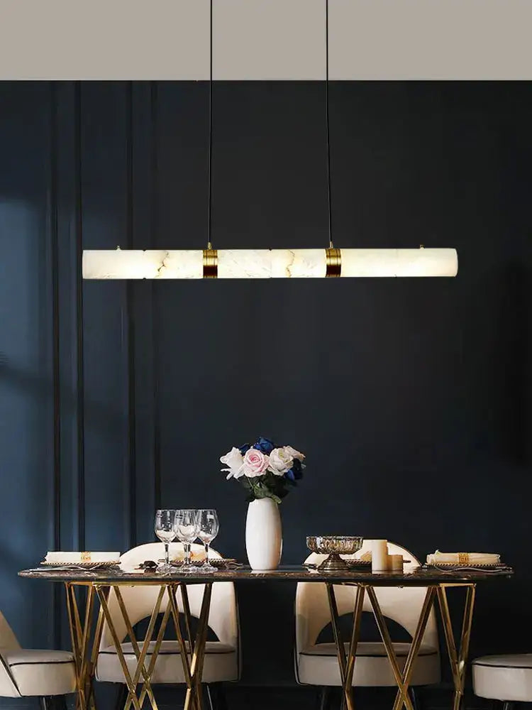 Decorbites led marble hanging lamps feature a sleek white alabaster finish with gold accents above a dining table