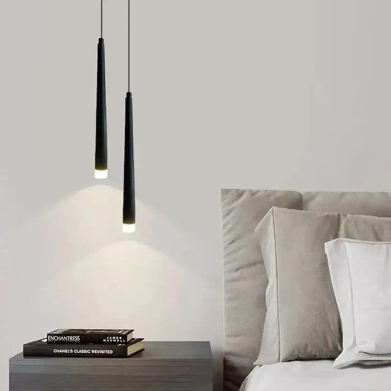 Two sleek black cylindrical decorbites led minimalist pendant lamps hang above a nightstand for bedroom lighting
