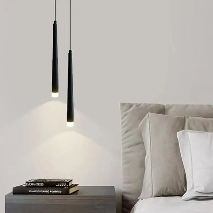 Two sleek black cylindrical decorbites led minimalist pendant lamps hang above a nightstand for bedroom lighting