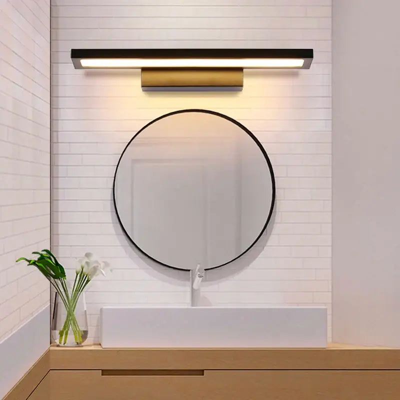 Modern black and brass decorbites led mirror wall lamp mounted above a round mirror for bathroom makeup lighting