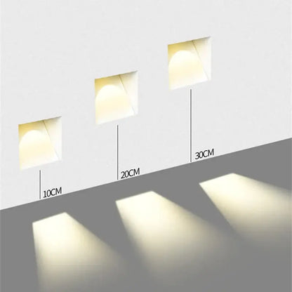 Three white DecorBites led motion sensor wall lamps with recessed square design and adjustable depths emitting warm glow