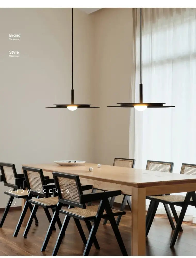 Modern black flying saucer chandelier with circular disc-shaped LED shades hanging above wooden dining table