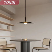 Black minimalist flying saucer chandelier with sleek disc-shaped design and warm glow by DecorBites™