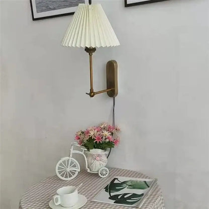 A cream-colored pleated lampshade mounted on a brass wall sconce for decorbites led origami wall lamp