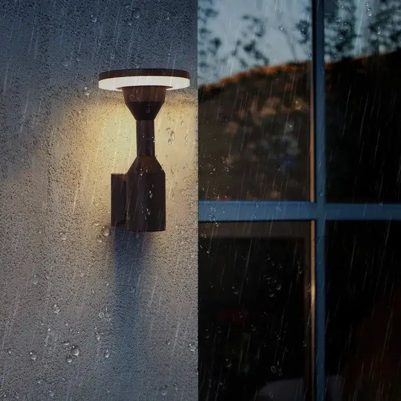 Modern black decorbites™ led outdoor wall lamp with circular illuminated top emitting warm light for garden use