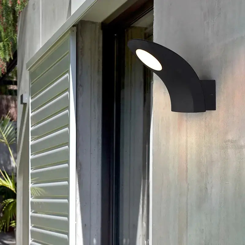 Black curved decorbites™ led outdoor wall lamp with bright white illuminated circular face and modern design