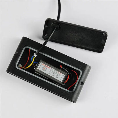 Black rectangular led driver with wiring and label inside open black plastic casing of decorbites led outdoor wall light