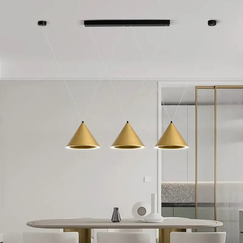 Three modern gold cone-shaped decorbites led pendant lights hang symmetrically above a dining table for minimalist decor