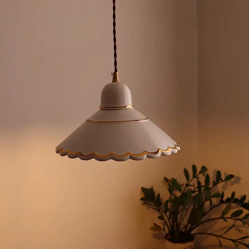 Decorbites led pendant lamp with off-white ceramic scalloped edge and gold trim hanging from twisted brown cord