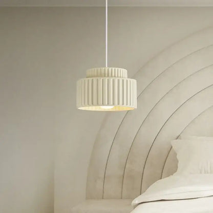 Cream-colored ribbed DecorBites led pendant lamp with modern resin design hanging above the bed