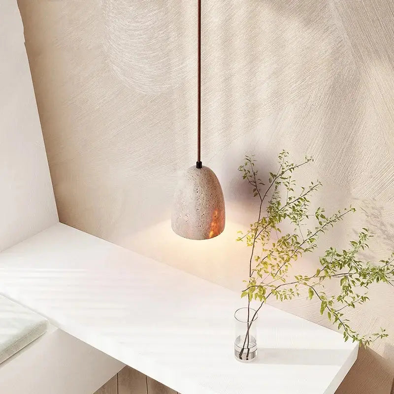 Minimalist decorbites led pendant lamp in yellow travertine with a warm glowing interior and textured concrete surface