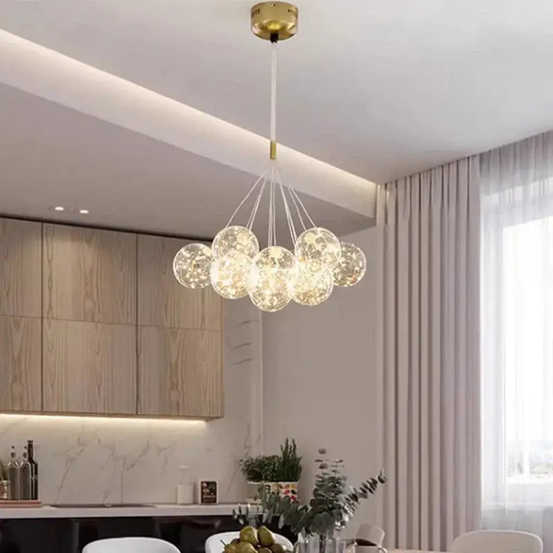 A modern DecorBites led pendant light chandelier with clear glass globes and gold ceiling mount for living and dining rooms