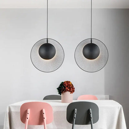 Two black circular wireframe decorbites led pendant lights hang above the dining table for loft bedroom decor