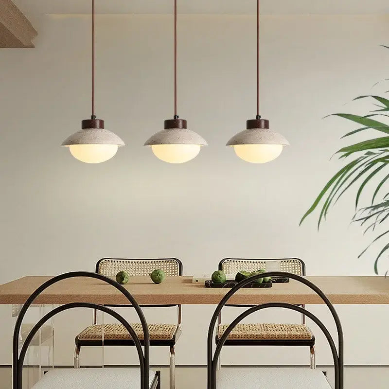Three decorbites led pendant lights with textured concrete shades and warm glow hang above a dining table
