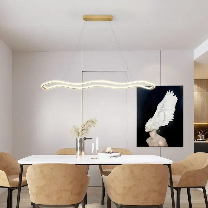 Modern gold-toned aluminum decorbites led pendant light with sleek wavy design hanging above dining table chandelier
