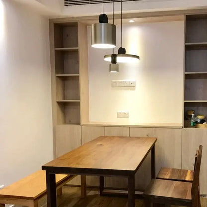 Modern minimalist decorbites led pendant lights with brushed metal cylindrical and disc shades above wooden table