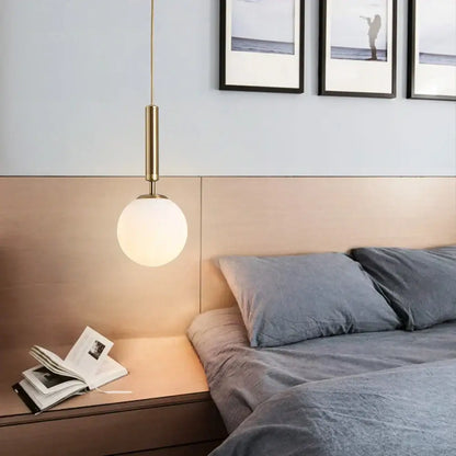 A modern decorbites led pendant light with brass cylindrical stem and frosted glass globe shade for dining room