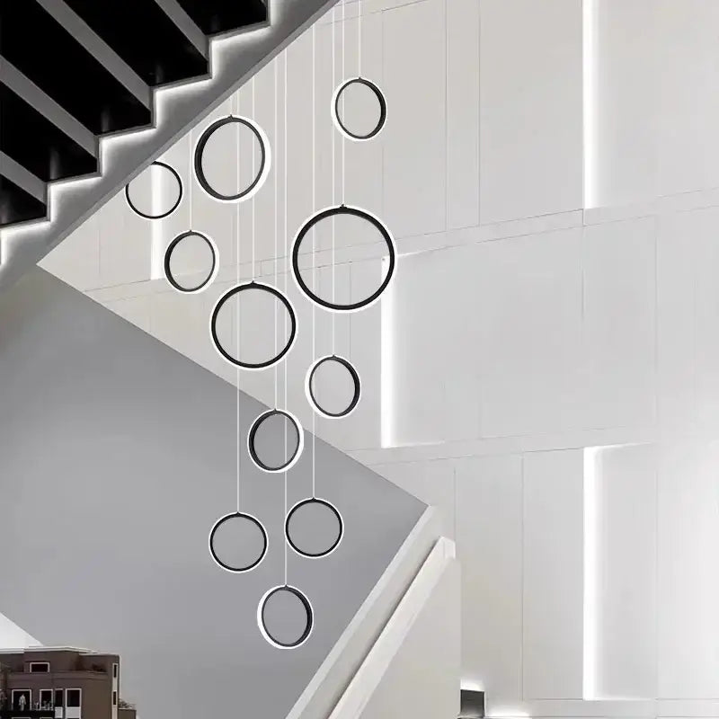 Modern black and white DecorBites™ led pendant lights in a cascading circular design above staircase chandelier