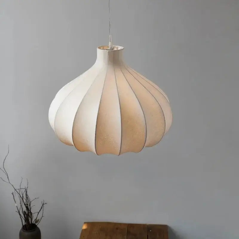 A modern off-white DecorBites led pendant light with pleated fabric shade and metallic fixture for stylish lighting