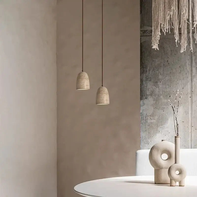 Two decorbites led pendant lights with textured off-white concrete shades hang on thin cords for vintage decor