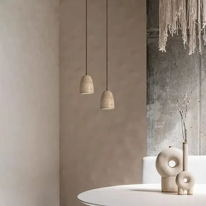 Two decorbites led pendant lights with textured off-white concrete shades hang on thin cords for vintage decor