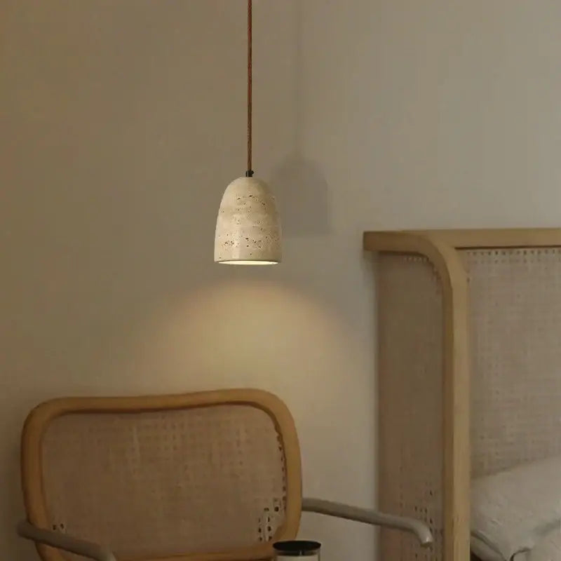 A beige textured concrete decorbites led pendant light with speckled finish hanging from a dark cord