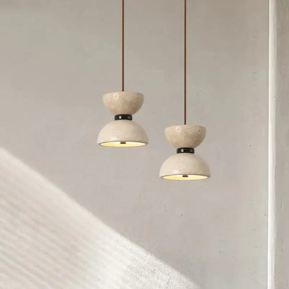 Two off-white textured stone decorbites led pendant lights with black metal accents and brown cords for living room use