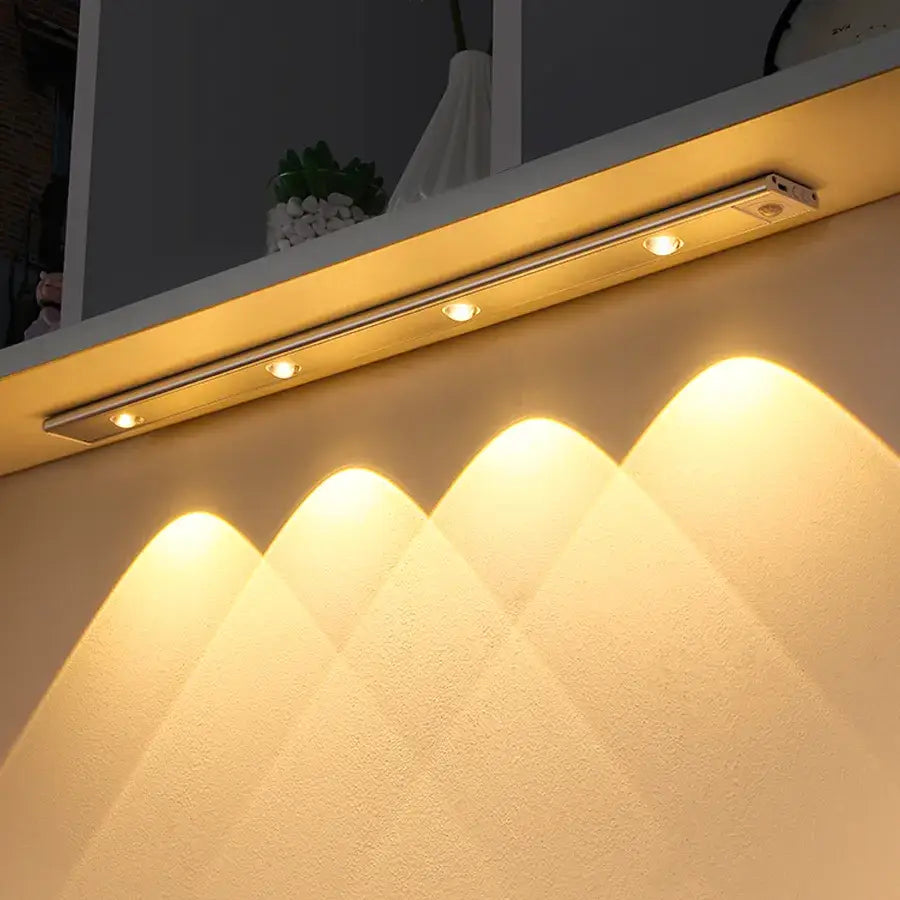 A sleek silver metallic decorbites led pir motion sensor cabinet light with four warm white spotlights under a shelf