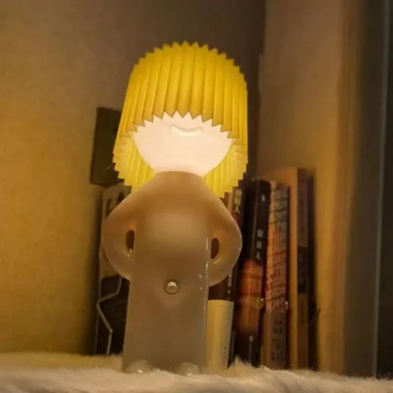 Decorbites led pleats table lamp features a translucent beige cartoon figure with bright yellow pleated hair for bedroom use