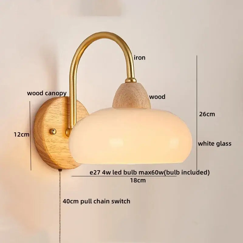 A warm-toned decorbites led pull chain wall light with brass iron arm wooden base and opaque white glass shade for bedroom decor